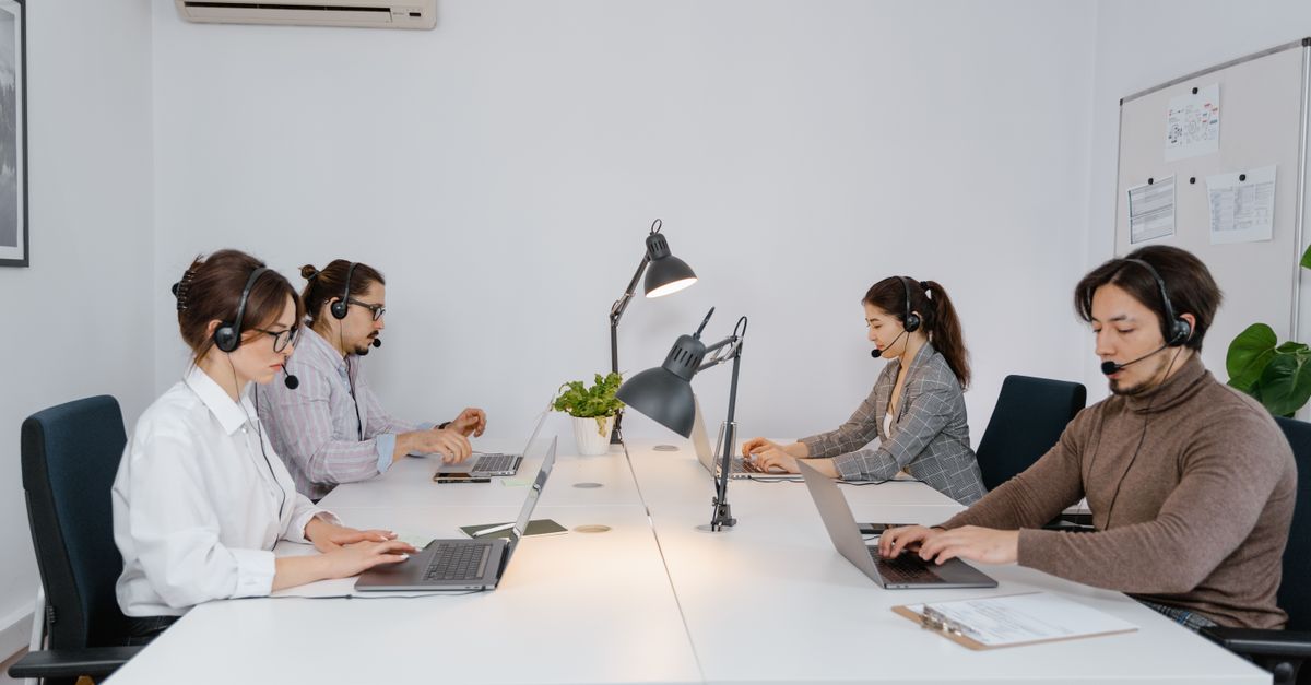 A diverse group of professionals working on laptops in a modern call center office.