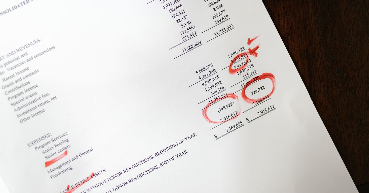 Financial statement with red annotations on a wooden table.